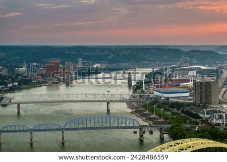 Downtown district of Cincinnati city in Ohio, USA at sunset with driving cars traffic on bridge and brightly illuminated high skyscraper buildings. American travel destination.