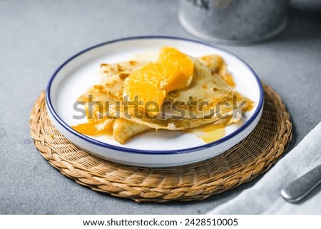 Delicious crepes suzette with orange syrup on plate Royalty-Free Stock Photo #2428510005
