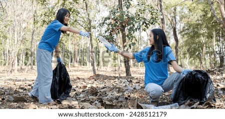 A group of Asian volunteers collects trash in plastic bags and cleaning areas in the forest to preserve the natural ecosystem.