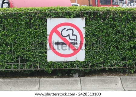 No Smoking Sign placed on green fence in outdoor area