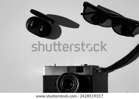 Wireless headphones, sunglasses and a film camera on a white background