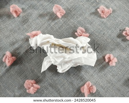 
Shabby white tissue that has been used is placed on a gray cloth and has pink decorations