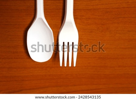 Photo of white spoon and fork on wood background.