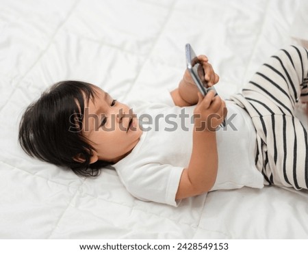 toddler baby using and watching smartphone on a bed