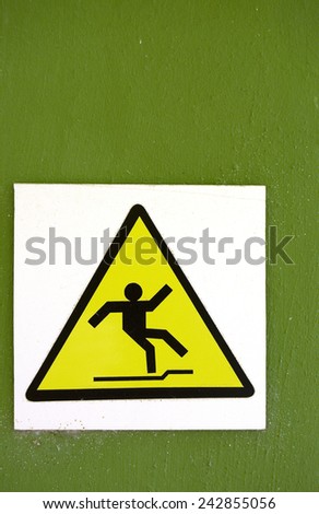 Slippery Yellow Sign on Green Wall Near a Swimming Pool in Cuba