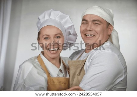 Cute oriental family with wife and husband cooking in the kitchen on Ramadan, Kurban-Bairam, Eid al-Adha. Funny couple of cooks at joke photo shoot. Pancakes, pastries, Maslenitsa, Easter