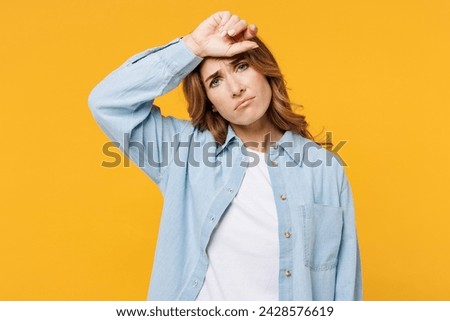 Young sad sick ill tired upset woman she wear blue shirt white t-shirt casual clothes put hand on forehead suffer from headache isolated on plain yellow background studio portrait. Lifestyle concept