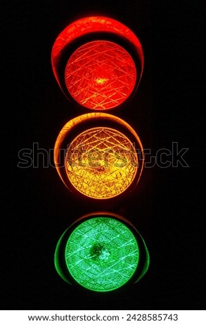 All three lights of a traffic light when illuminated with a black background