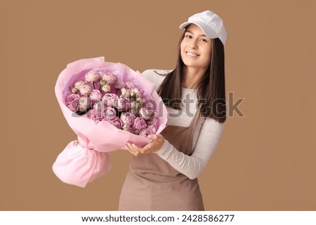 Young delivery woman with bouquet of beautiful roses on brown background