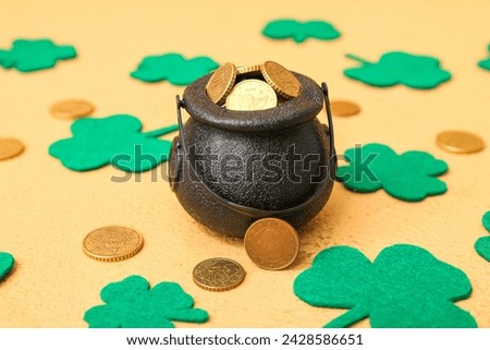 Leprechaun pot with golden coins and clover leaves on beige background. St. Patrick's Day celebration