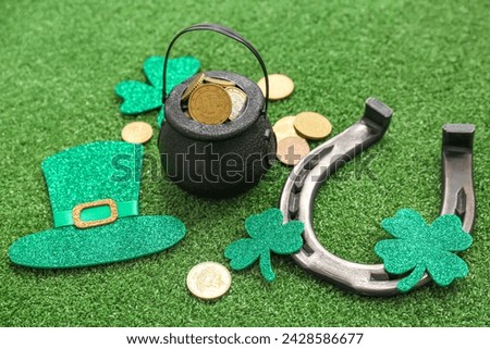Pot with golden coins, horseshoe and decor on grass. St. Patrick's Day celebration