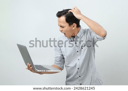angry mad asian man holding laptop computer on isolated background