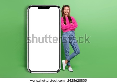 Full size photo of positive girl wear pullover hold arms crossed near smartphone display empty space isolated on green color background