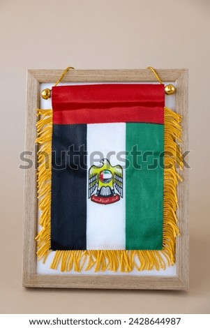National symbol of UAE. United Arab Emirates small flag with Peregrine falcon on neutral beige background. Copy space for your text. Concept of Independence 