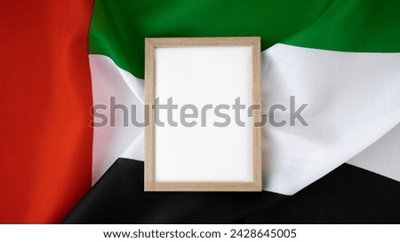 Empty white paper frame template National symbol of UAE. United Arab Emirates small flag with Peregrine falcon on neutral beige background. Copy space for your text. Concept of Independence  Royalty-Free Stock Photo #2428645005