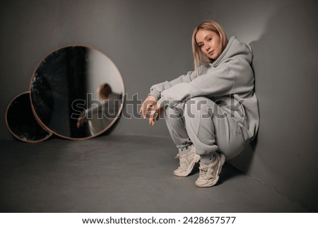 girl in a gray sports suit on a neutral background
