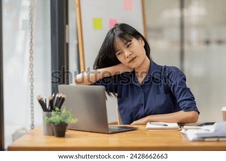 A female employee stretching lazy at the desk to relax while working in the office. Feeling stressed and achy from work.