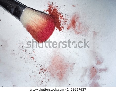  closeup of beauty tools brush and powder blush scattered on a white background