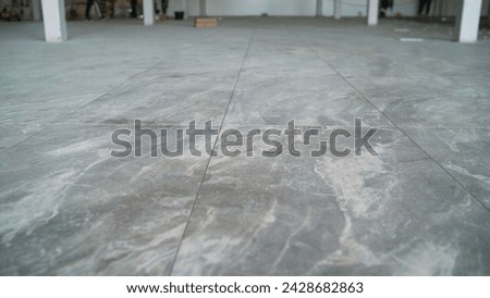 Laying large format tiles, gray. New renovation project with tiled floors, large format ceramic tiles. Modern new tiles. Royalty-Free Stock Photo #2428682863