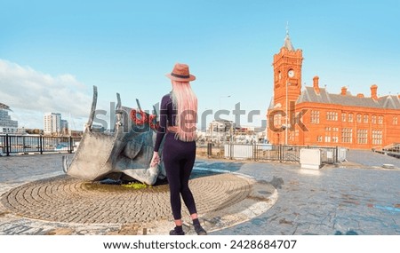 A beautiful blonde woman with a stylish hat wearing black tight trousers walking on the street  - Merchant Seafarers’ War Memorial - Cardiff, Wales