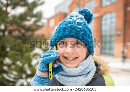 happy 11 year old boy talking on smartphone in winter outside