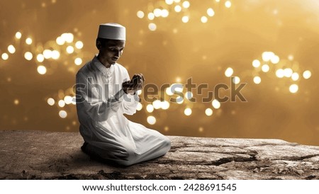 Muslim man sitting and raised her hands and prayed to Allah with a blurred light background. Muslim concept