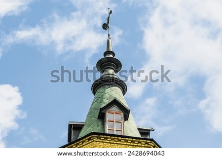It is view of old brick tower with weather vane on top.  Its a cloudy sky. It's photo of tower of the National Technical University of Ukraine ("Igor Sikorsky Kyiv Polytechnic Institute")