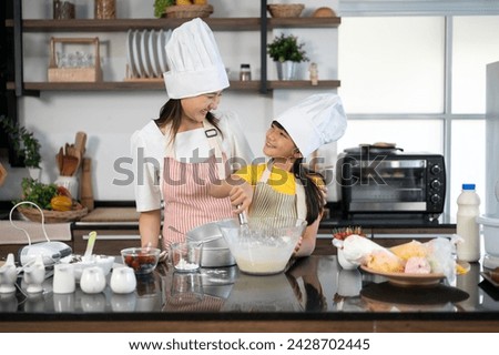 A little girl helping mother preparation baking in holidays. Mother teaching little daughter how to mix flour for baking cookies in kitchen at home. Children learning cooking concept