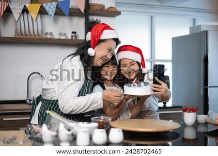 Happy Grandmother, mother and little daughter taking photo through smartphone while finish decorated cake for Christmas day. Three generations Asian women taking selfie through smartphone