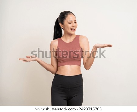 Young beautiful smiling asian woman with sportswear hand palm up with copy space on isolated. Happy healthy slim fit and firm latin attractive sporty woman standing pose exercise workout in studio. Royalty-Free Stock Photo #2428715785