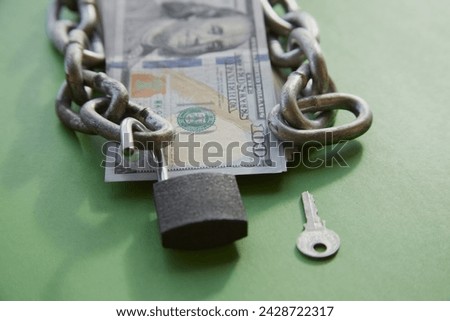  Hundred-dollar bills with a chain on them and an open lock and key nearby on green cloth, unlocking funds, unlocked money, unlocking an account Royalty-Free Stock Photo #2428722317