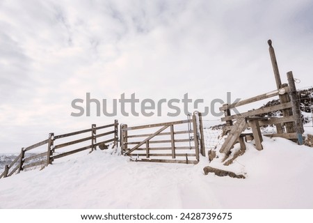 Timber gate and step-over platform forming entrance to Hole of Horcum, a natural depression and attraction, following snow storm near Goathland, Yorkshire, UK. Royalty-Free Stock Photo #2428739675