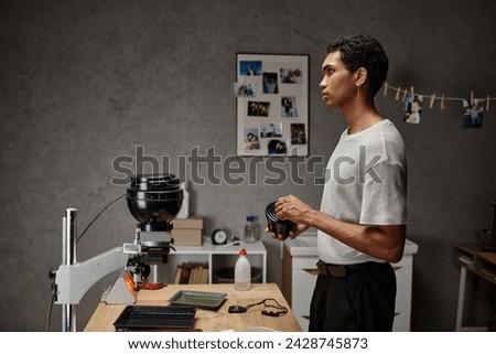handsome young african american photographer securing a film canister lid in a darkroom