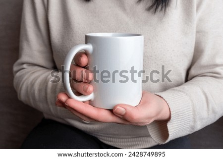 Woman's hands hold a pristine white mug, providing a perfect canvas for promoting mug designs