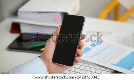 A businessman holds a new smartphone in his hand The mobile application market shows a display you can insert your image for advertising or financial statistics.