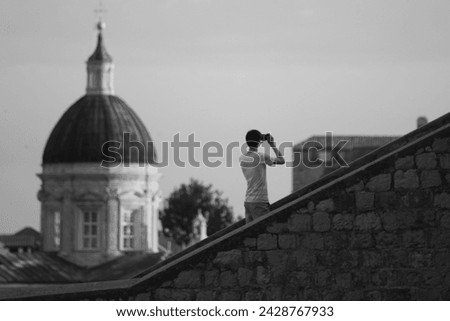 Black and White picture of a man taking photograph having big church as a backgroud