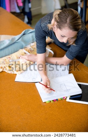 Fashion designer and drawing costume design with style, artistic or inspiration at desk with mockup. Pencil, female person or fabric with stylish, fashionable or pattern for clothing with creativity