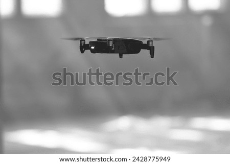Flying drone inside a building in black and white. Flying quadro copter close up. Royalty-Free Stock Photo #2428775949