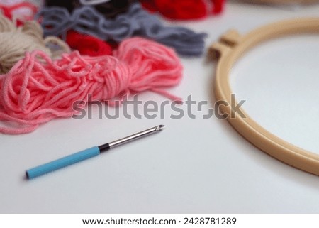 Colorful wool, embroidery hoop and punch needle on white background. Punch needle kit. Selective focus.