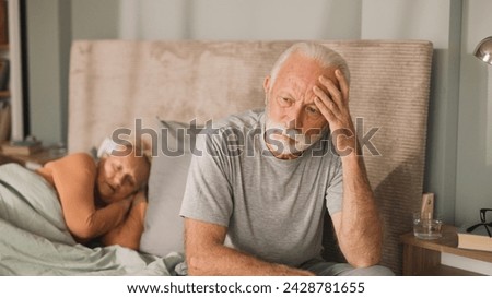 Senior man sitting on bed looking worried Royalty-Free Stock Photo #2428781655