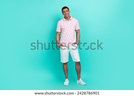 Full length photo of positive man wear flamingo print t-shirt white shorts hold arms in pockets isolated on turquoise color background