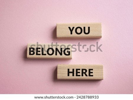 You belong here symbol. Wooden blocks with words You belong here. Beautiful pink background. Business and You belong here concept. Copy space.