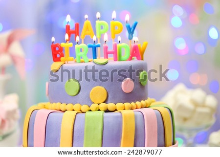 Delicious birthday cake on shiny light background
