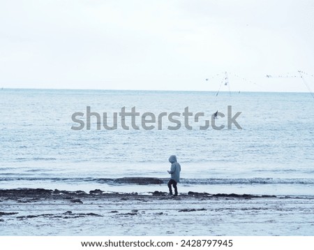 A boy walks along the snowy seashore