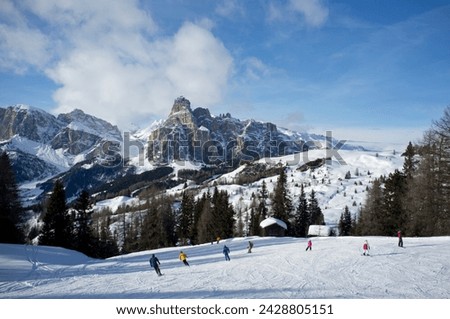Skiers at the alta badia ski resort with sassongher mountain in the distance, dolomites, south tyrol, italy, europe