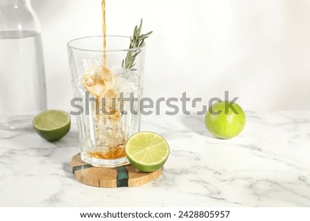 Pouring coffee into glass with ice cubes at white marble table. Space for text