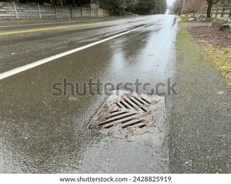 Storm drain catch basin on the side of the road Royalty-Free Stock Photo #2428825919