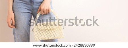 Banner with handcraft bag made from pearl imitation beads in woman's hand in front of beige background. Place for text.