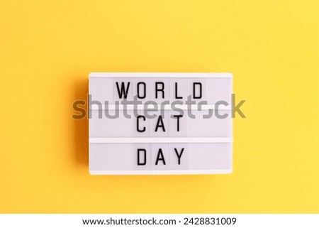 World cat day. White lightbox with letters on a yellow background. 