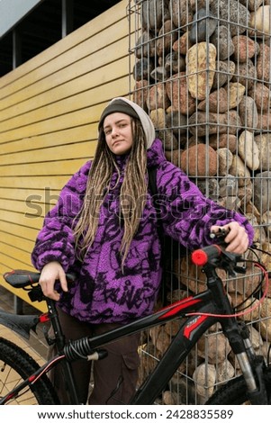 Cute young woman with piercings and dreadlocks rented a bike around the city